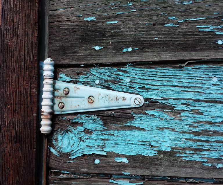 Rdjava metalna šarka na oljuštenim daskama.